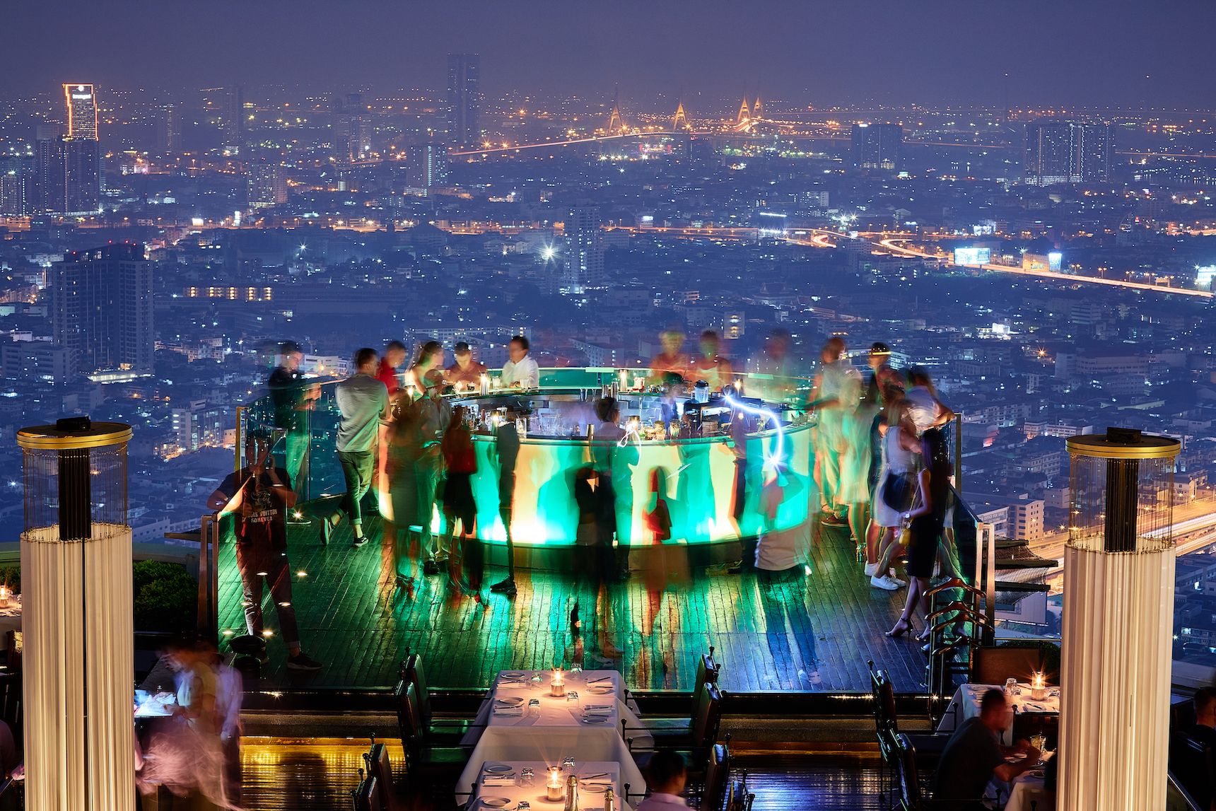 green light bar on edge of terrace surrounded by customers